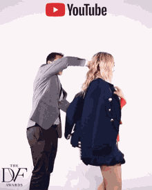 a man helps a woman put on a jacket with a youtube logo behind them