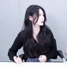 a woman with long black hair is wearing a black top