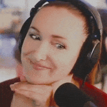 a woman wearing headphones and a microphone smiles for the camera