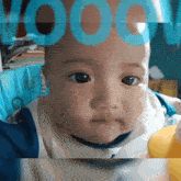 a baby is looking at the camera with the word vood written above his head