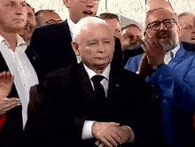 a man in a suit and tie is shaking hands with another man in a crowd .