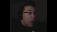 a man wearing glasses and headphones is making a surprised face .