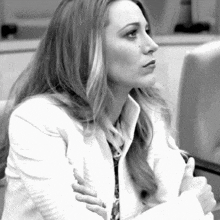 a black and white photo of a woman sitting with her arms crossed