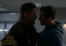 two men kissing with one wearing a jacket with an american flag patch on it