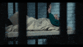 a man in a green shirt is laying on a bed with a white blanket