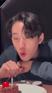 a young man is eating a piece of cake with a cherry on top