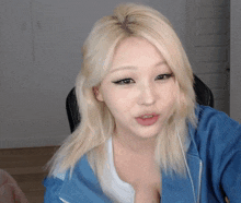 a woman with blonde hair is wearing a blue jacket and white shirt