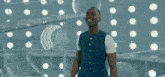 a man in a blue and white striped vest is smiling in front of a wall of lights