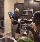 a man and a woman are dancing in a kitchen with a watermelon