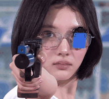 a woman wearing glasses is holding a gun in her hand