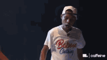 a man wearing a white t-shirt with the words `` shut the baboon clothing '' on it is standing on stage .