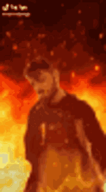 a man with a beard is standing in front of a fire background .
