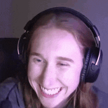 a woman wearing headphones is smiling and looking at the camera