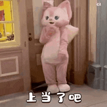 a pink bunny mascot is standing in front of a door and giving a thumbs up .