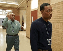 two men are standing in a hallway and one has a name tag that says ' a. j. ' on it