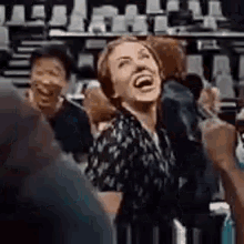 a woman is laughing while standing in front of a crowd .
