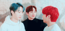 three young men with different hair colors are standing next to each other .