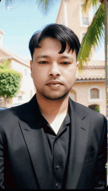 a man in a black suit is standing in front of a building