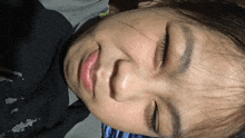 a close up of a person 's face with their eyes closed and a black shirt on