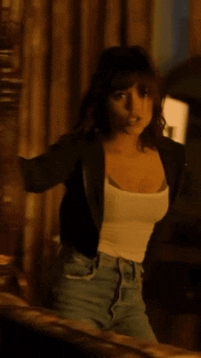 a woman in a white tank top and jeans is dancing