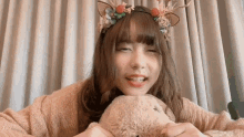 a girl wearing a headband with antlers on it holds a stuffed animal