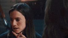 a woman looking at herself in a mirror with her finger on her chin