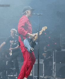 a man singing into a microphone while playing a guitar with the words time low visible in the background