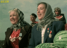 a woman wearing a medal stands next to another woman holding watermelon