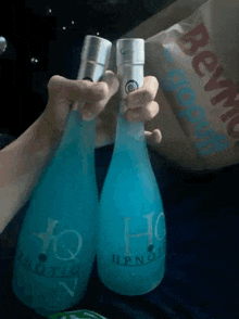 a person is holding two bottles of hypnotiq