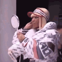 a woman is looking at herself in a mirror with the word fendi on her headband