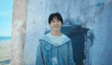 a young man wearing a blue hoodie is smiling in front of a building .