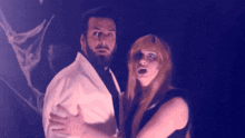 a man with a beard and a woman with red hair are standing next to each other in a dark room