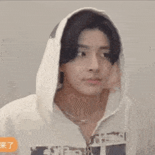 a young man wearing a white hoodie and a necklace is making a funny face .