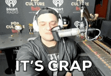 a man wearing headphones in front of a microphone with the words it 's crap below him