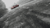 a red car with the number 8 on the side is driving down a snowy road