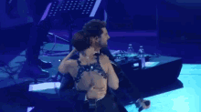 a man in a tuxedo is holding a woman on a stage