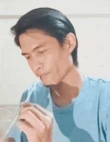 a man in a blue shirt drinks through a plastic straw