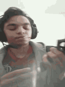 a young man wearing headphones is smoking a cigarette while holding a glass .