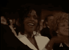 a woman is sitting in a crowd of people with her hands in the air and smiling .