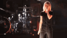 a woman singing into a microphone in front of a drum set with the letter g on it