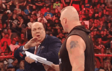 a man with a tattoo on his arm is holding a piece of paper and talking to another man