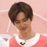 a young man wearing a pink shirt and a white shirt with a microphone around his neck is making a funny face .
