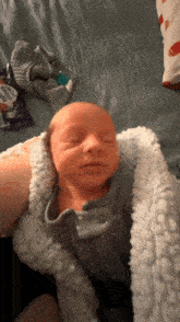 a baby is sleeping in a blanket with a bag of milky way popcorn in the background