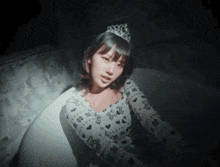 a woman with a tiara on her head is sitting in a bathtub