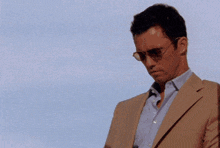 a man in a suit and sunglasses holds a motorola phone