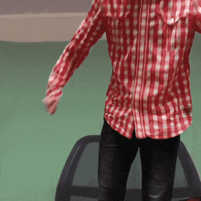 a man wearing a red and white checkered shirt with a logo on the left side