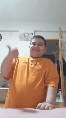 a young boy wearing an orange shirt that says ' abercrombie & fitch ' on it