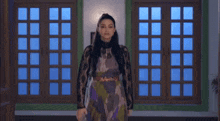 a woman in a lace dress is standing in front of a window .