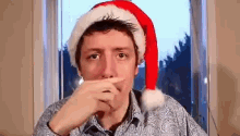a man wearing a santa hat covering his mouth