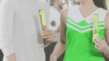 a woman in a green cheerleading uniform is holding a chocolate bar